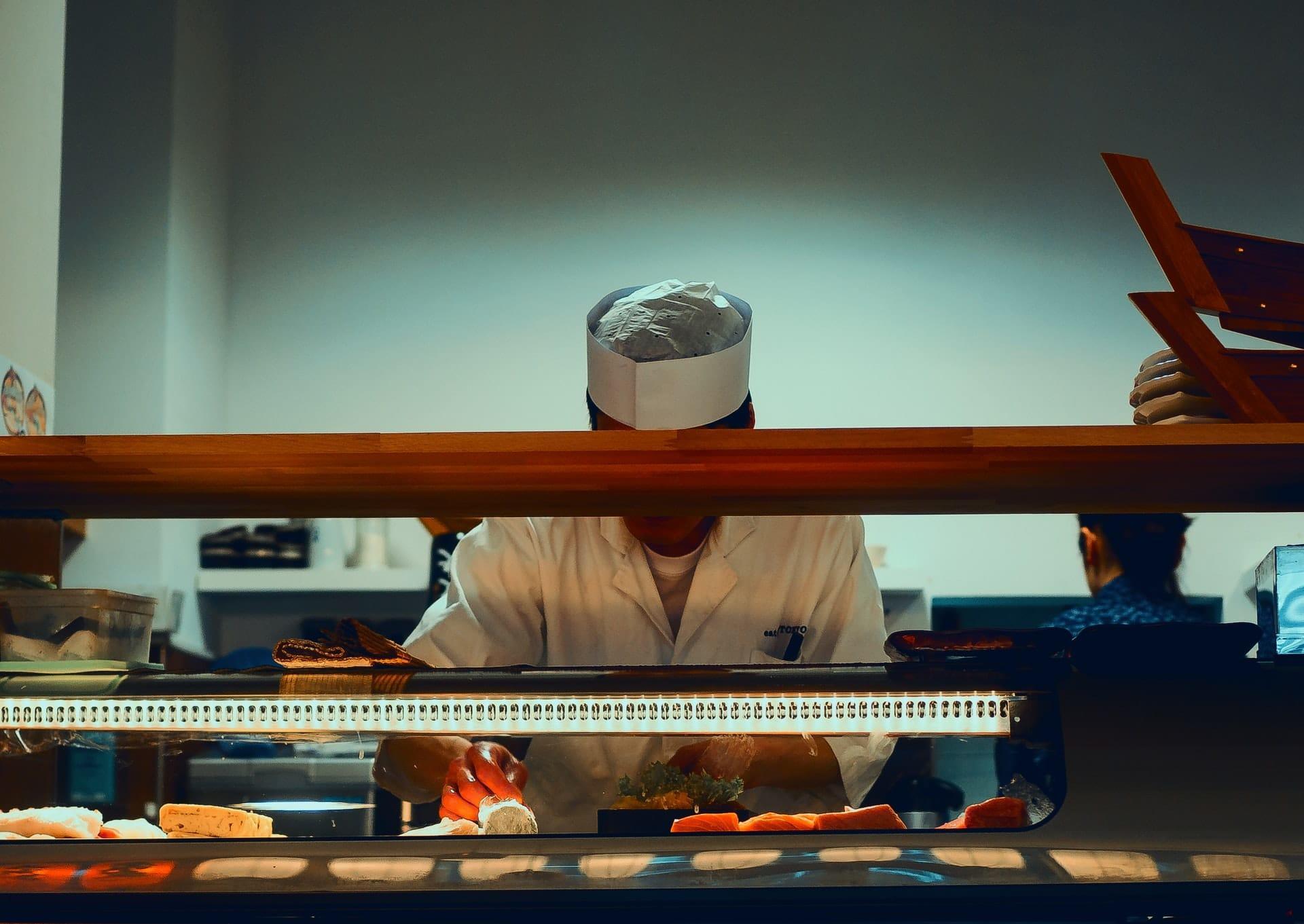 Chef standing behind the counter wearing a chef's uniform.