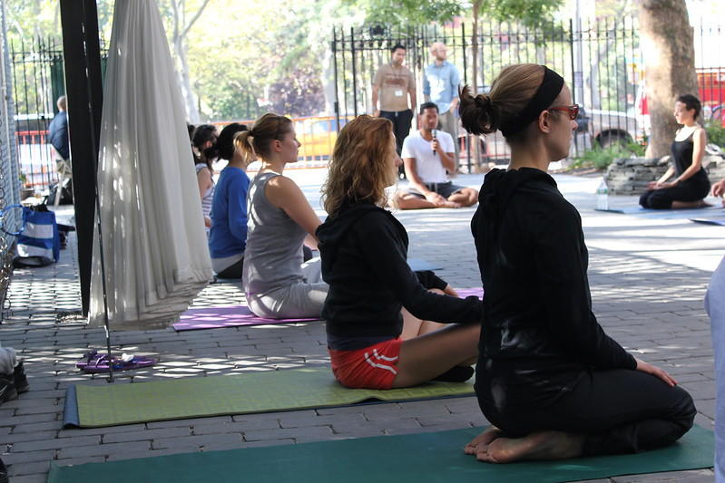 Students practice yoga in the outdoors of the city.
