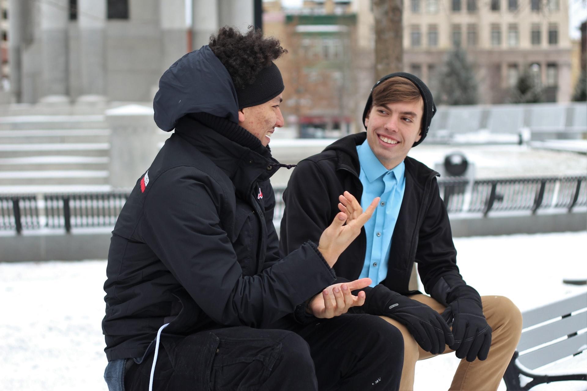 two men sitting, smiling, and talking