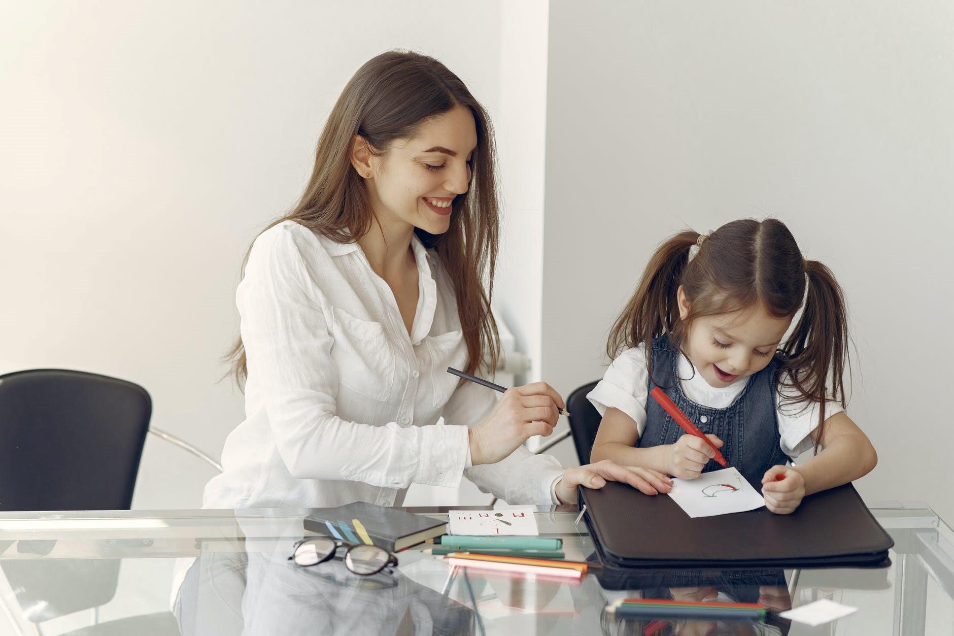 A woman helping a girl with her school assignments.