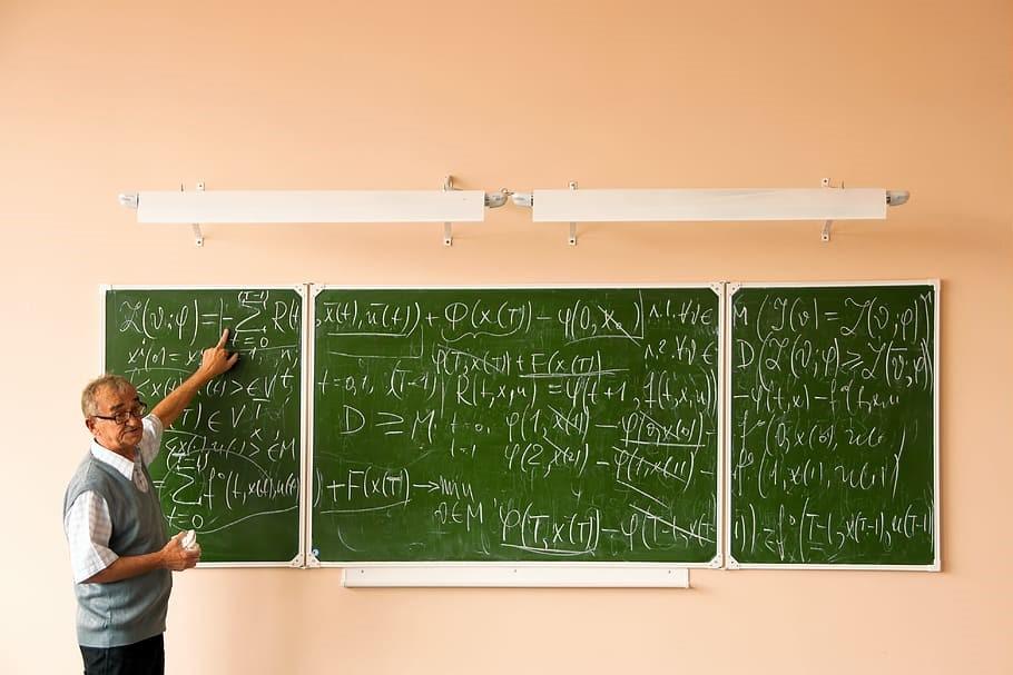 Math teacher teaching complex sums on a chalkboard