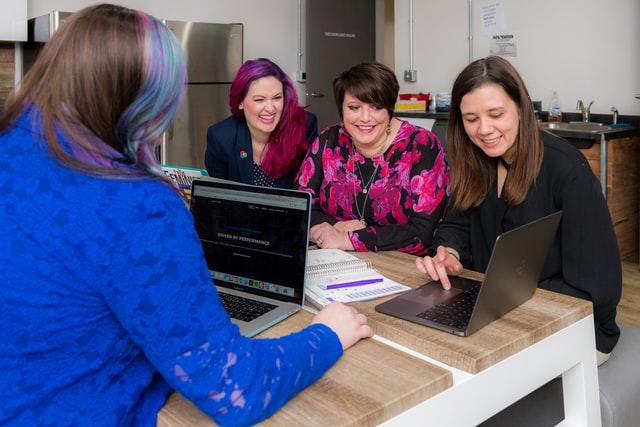 group of women sitting at a desk looking at laptop