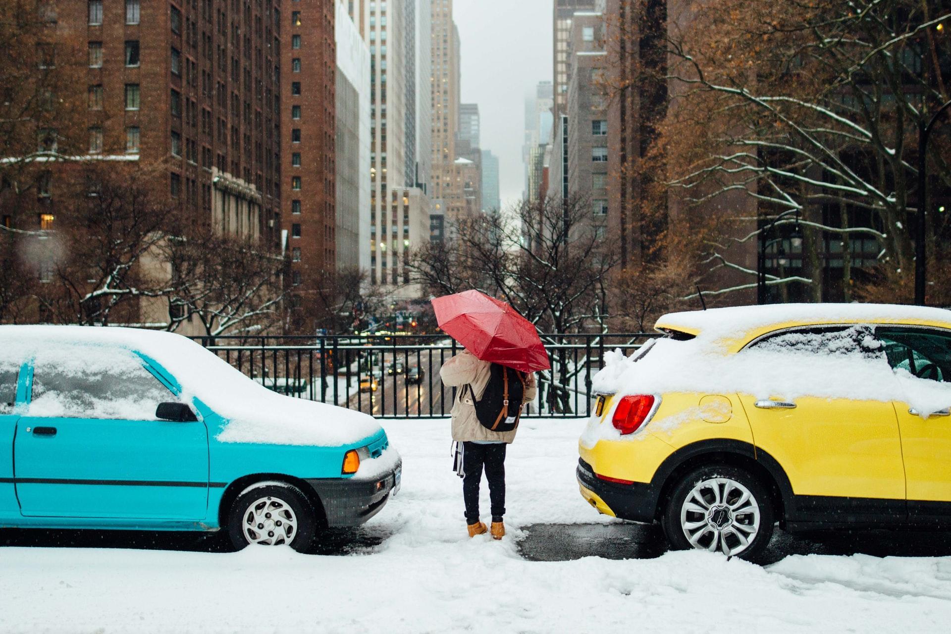 man standing in between two cars in snow