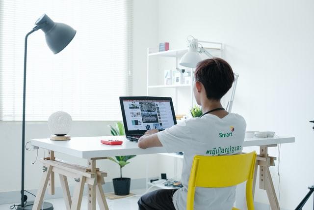 boy sitting in chair next to desk staring at laptop