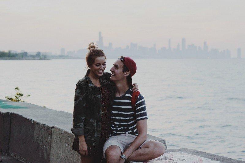 young couple sitting on ledge embracing and smiling