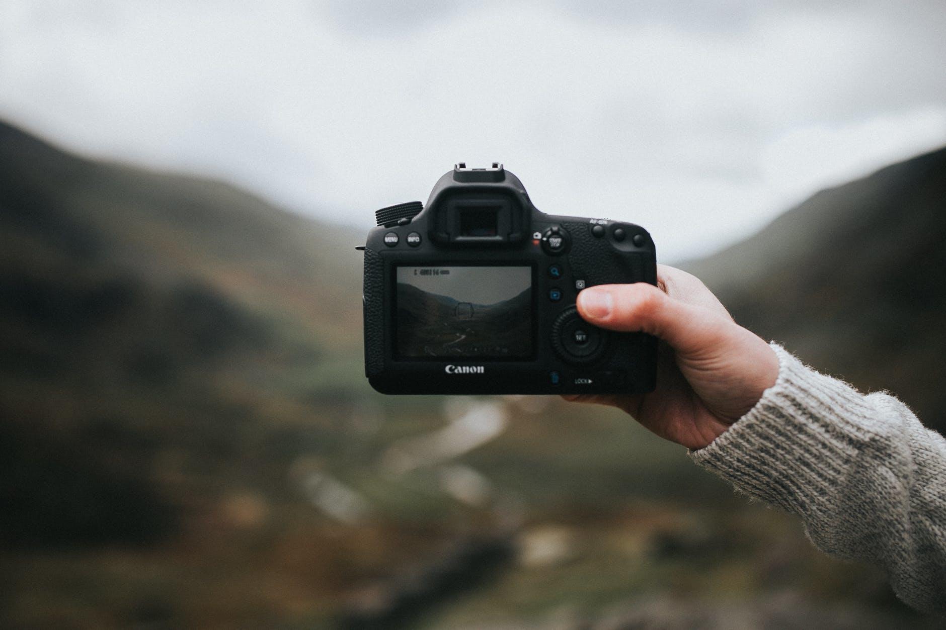 Photography teacher holding a camera in front of a landscape