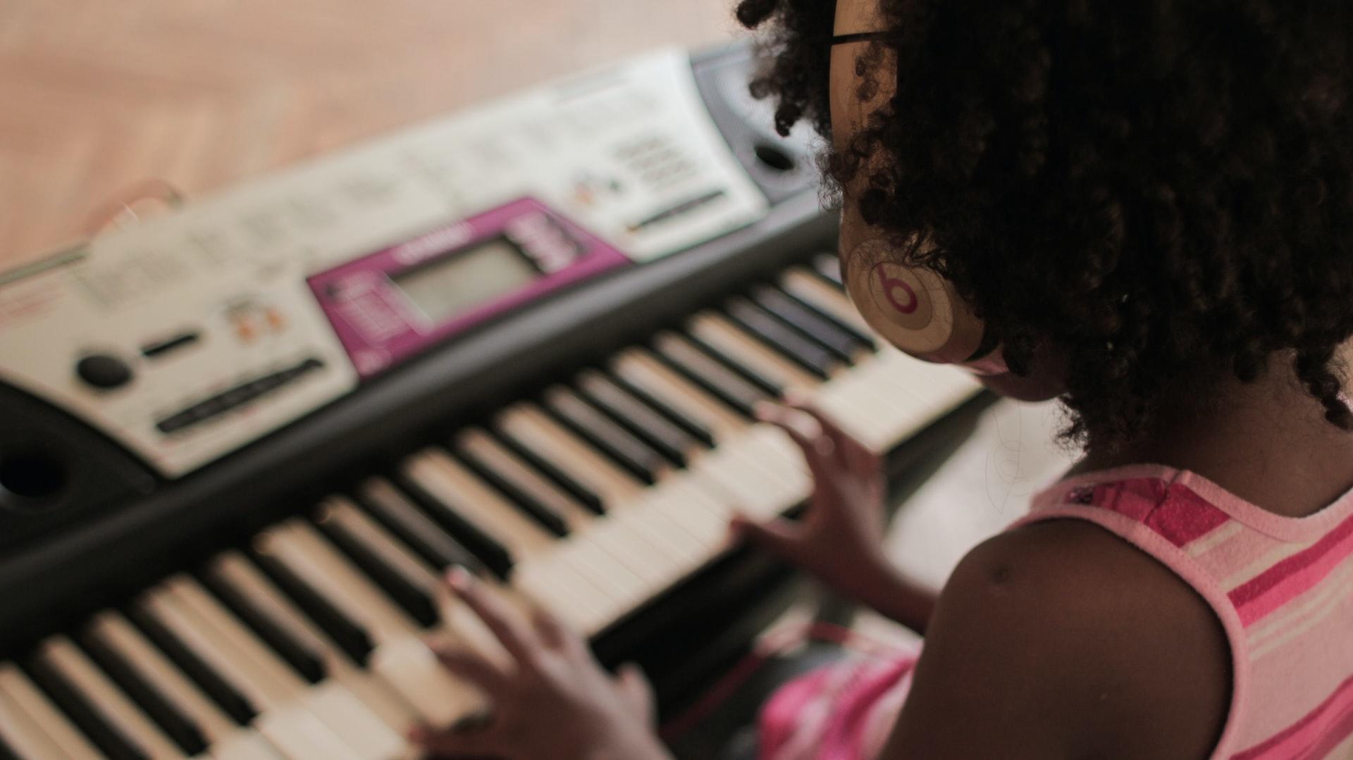 young girl playing keyboard wearing headphones