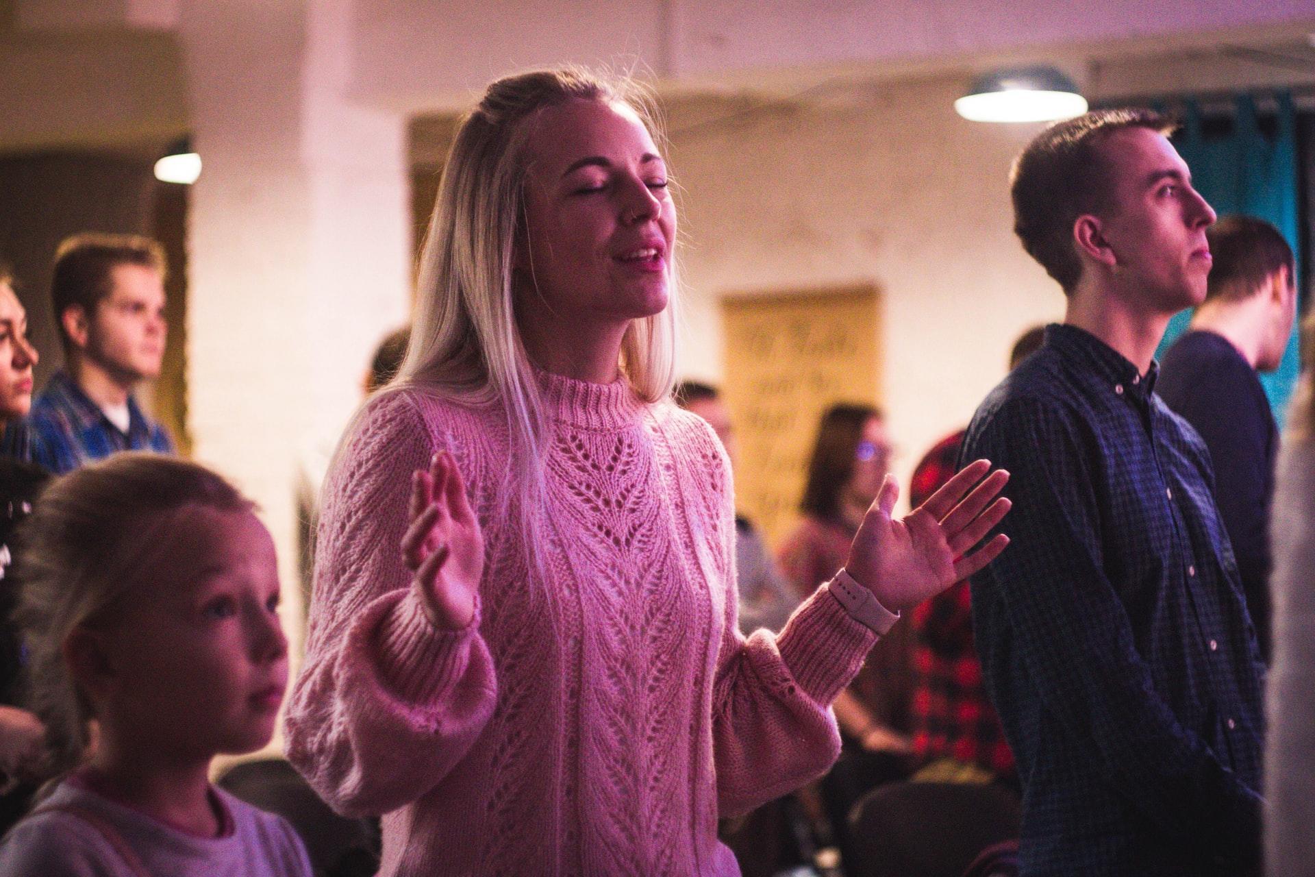 girl wearing pink sweater singing in a group