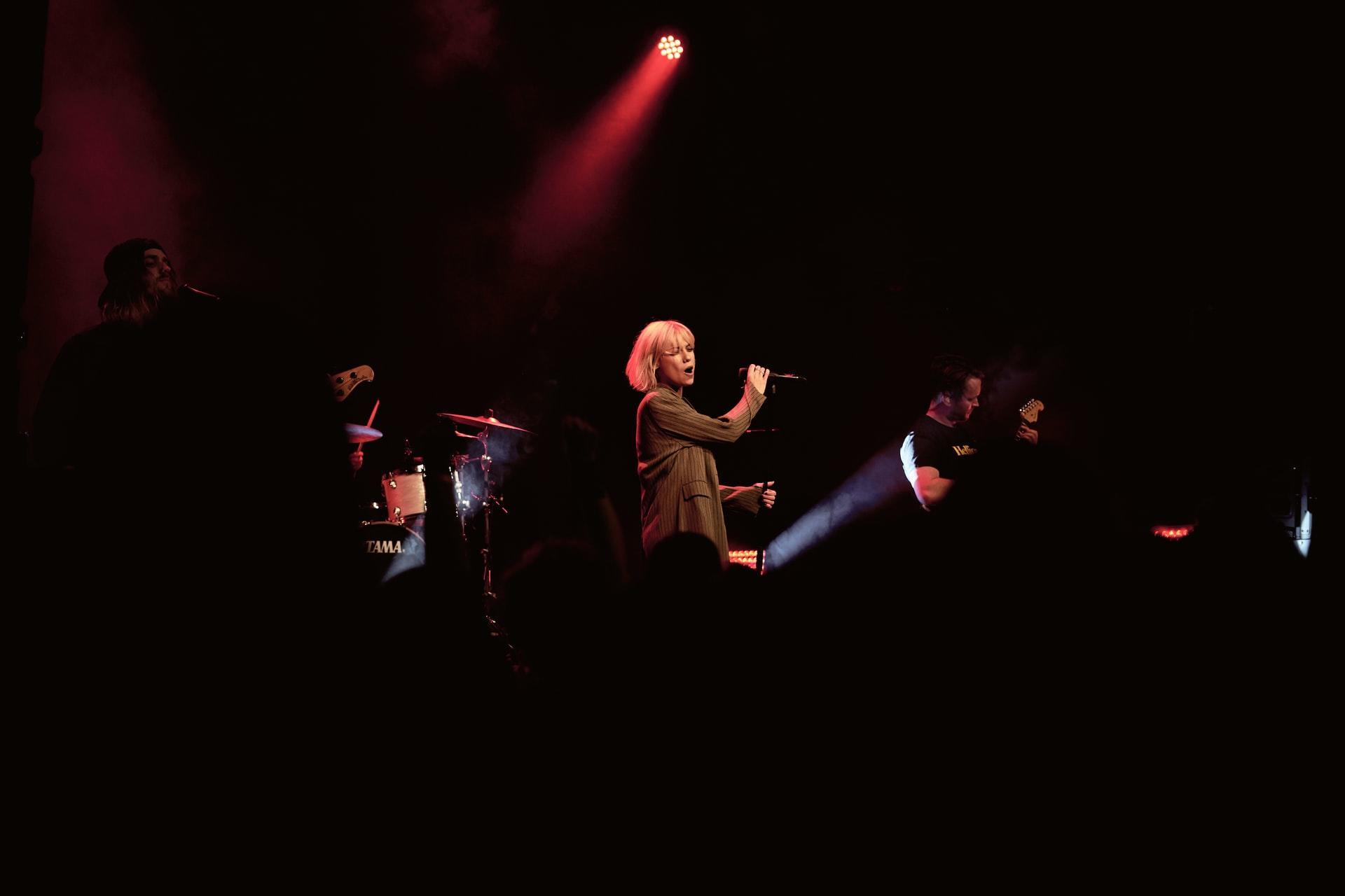 Lady singing on a stage in a dark room