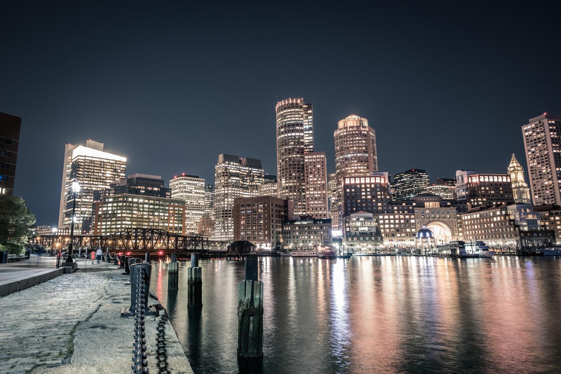 downtown shot of Boston at night next to the waterfront
