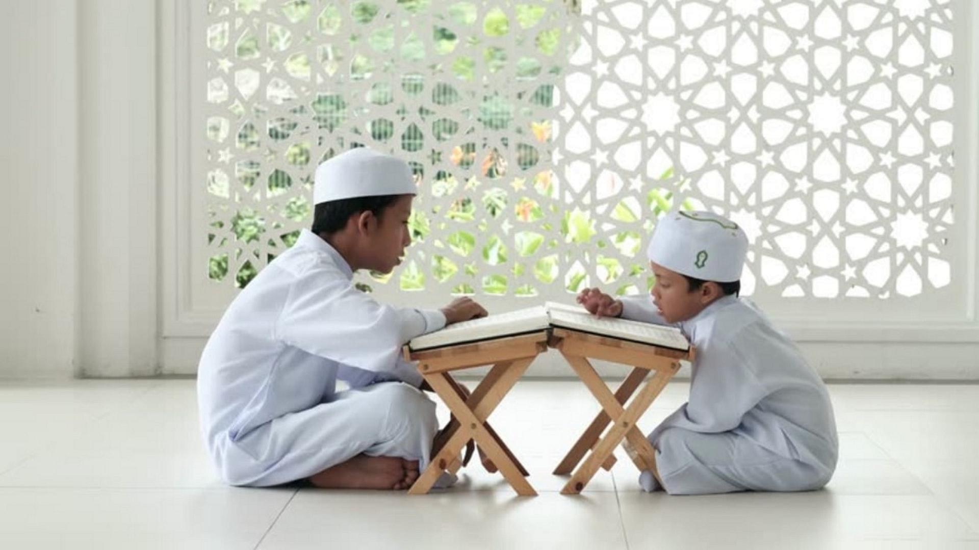 Two children sitting around a table studying the quran