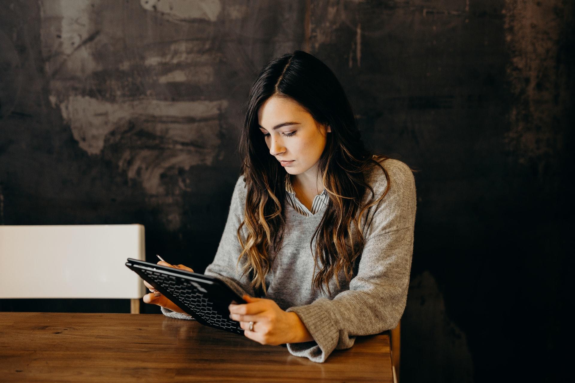 A woman sitting next to a table holding a tablet