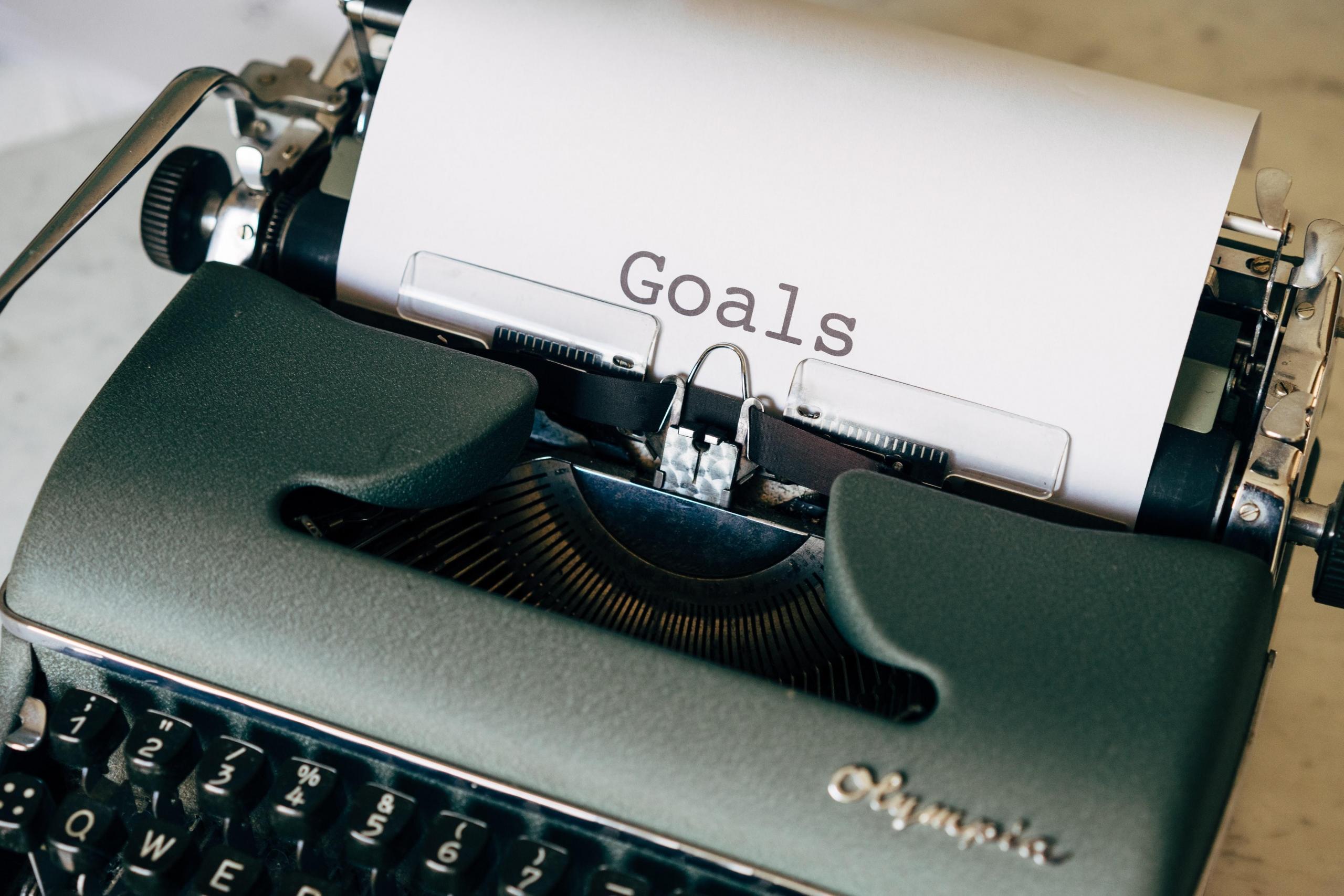 A typewriter that is holding a paper with the word 'Goals' written on it. Figure out your goals for the use of mathematics in your life. Is it to pass the subject, or to improve so you can major in it someday? 