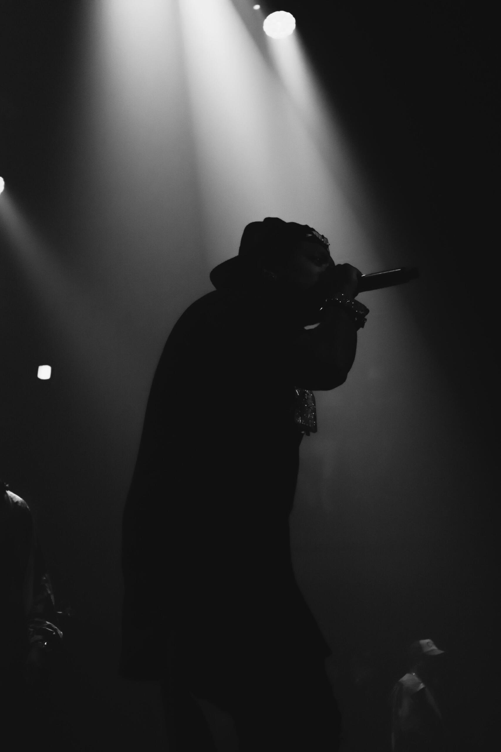 Monochrome image of a singer passionately performing into a microphone on stage.