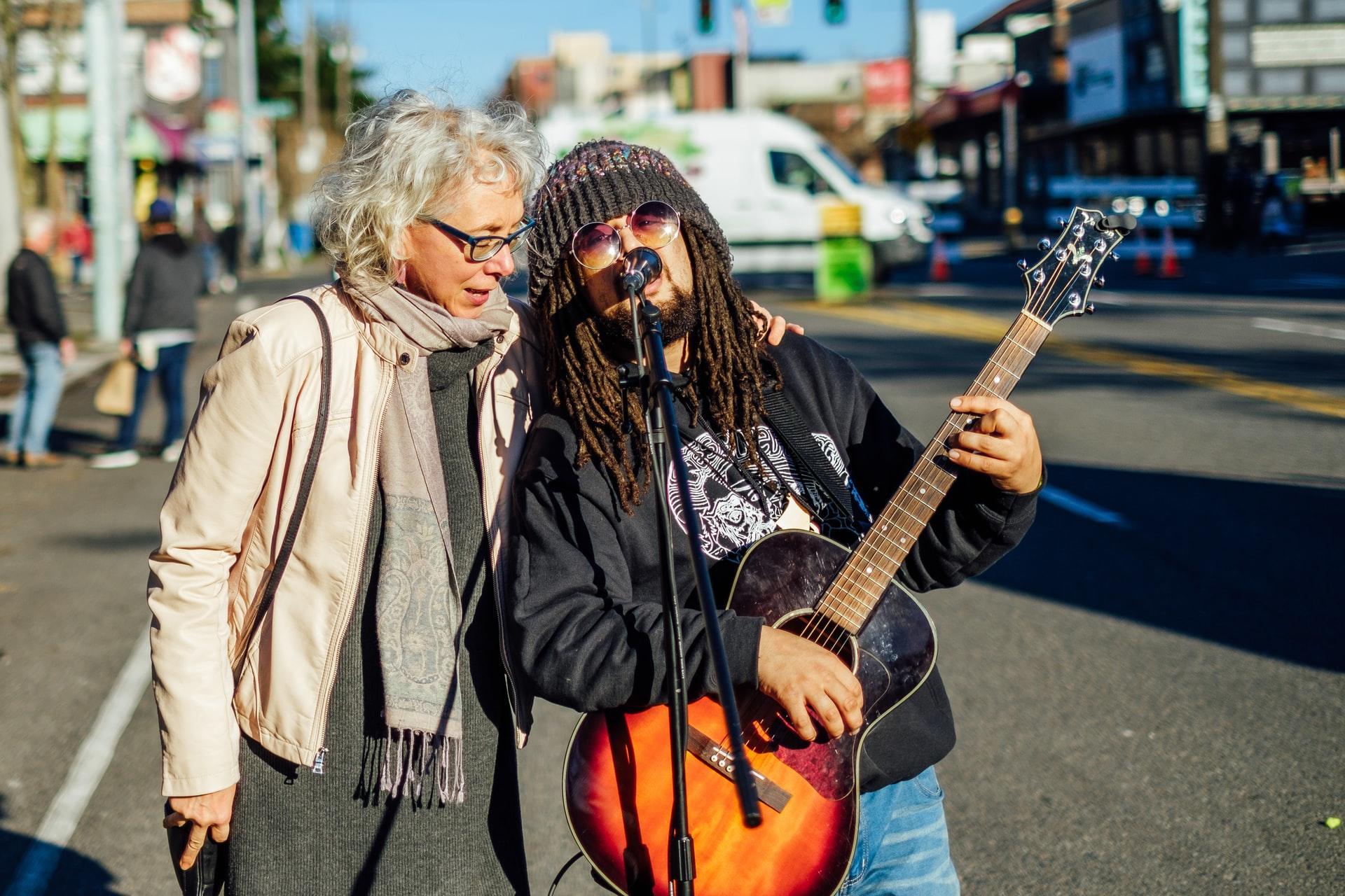 two women singing on the streets with a guitar