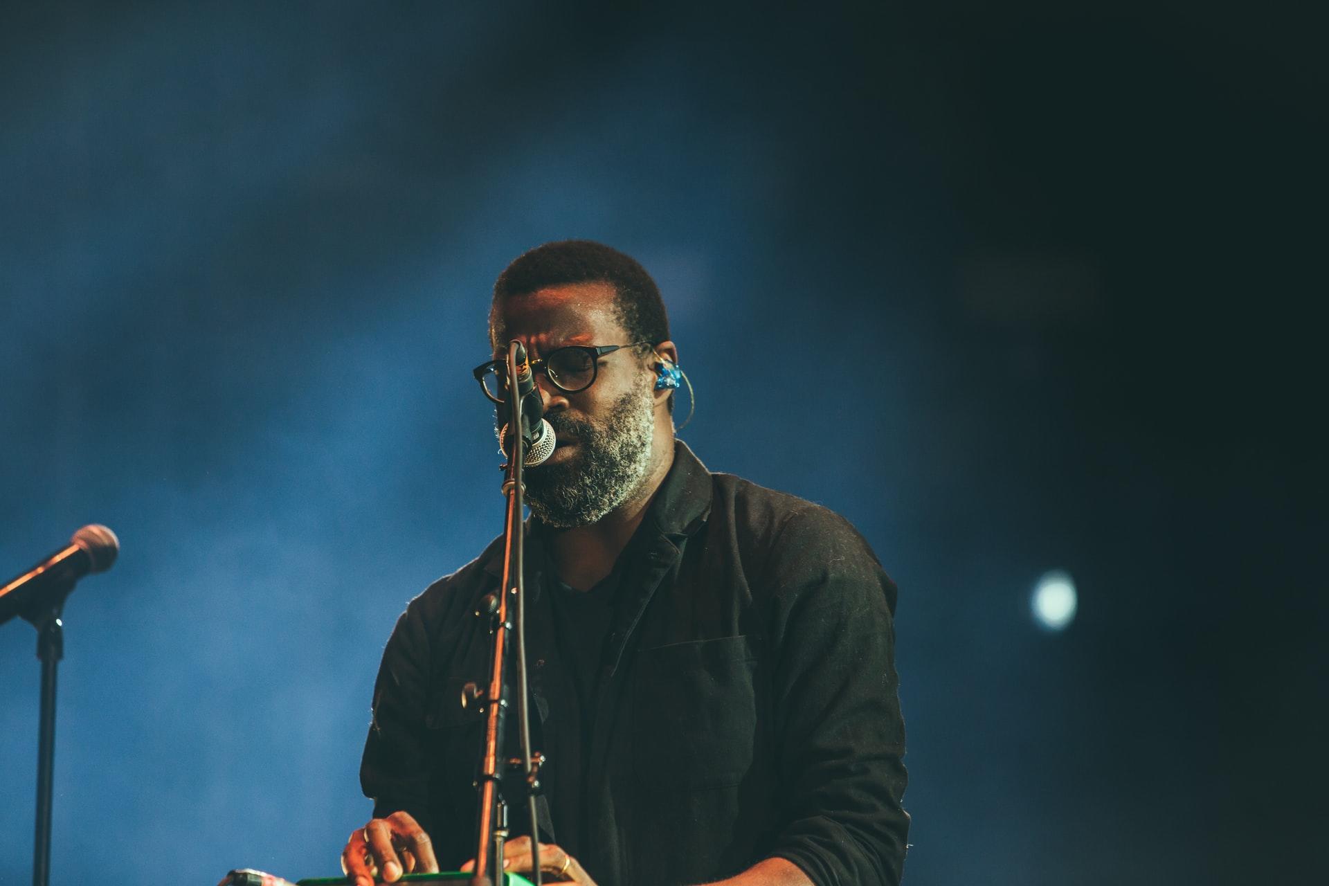 Man singing next to microphone in a dark room.