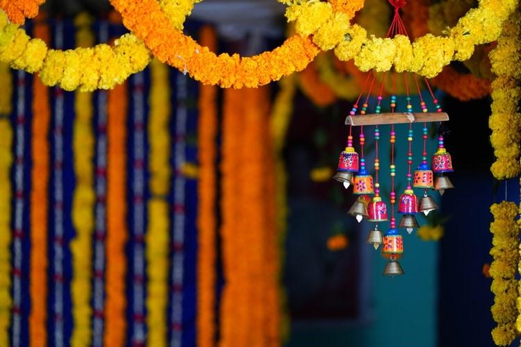 Colorful bells behind traditional decorative garlands of orange and yellow flowers. This shows the vibrancy and creativity of everyday life in India.