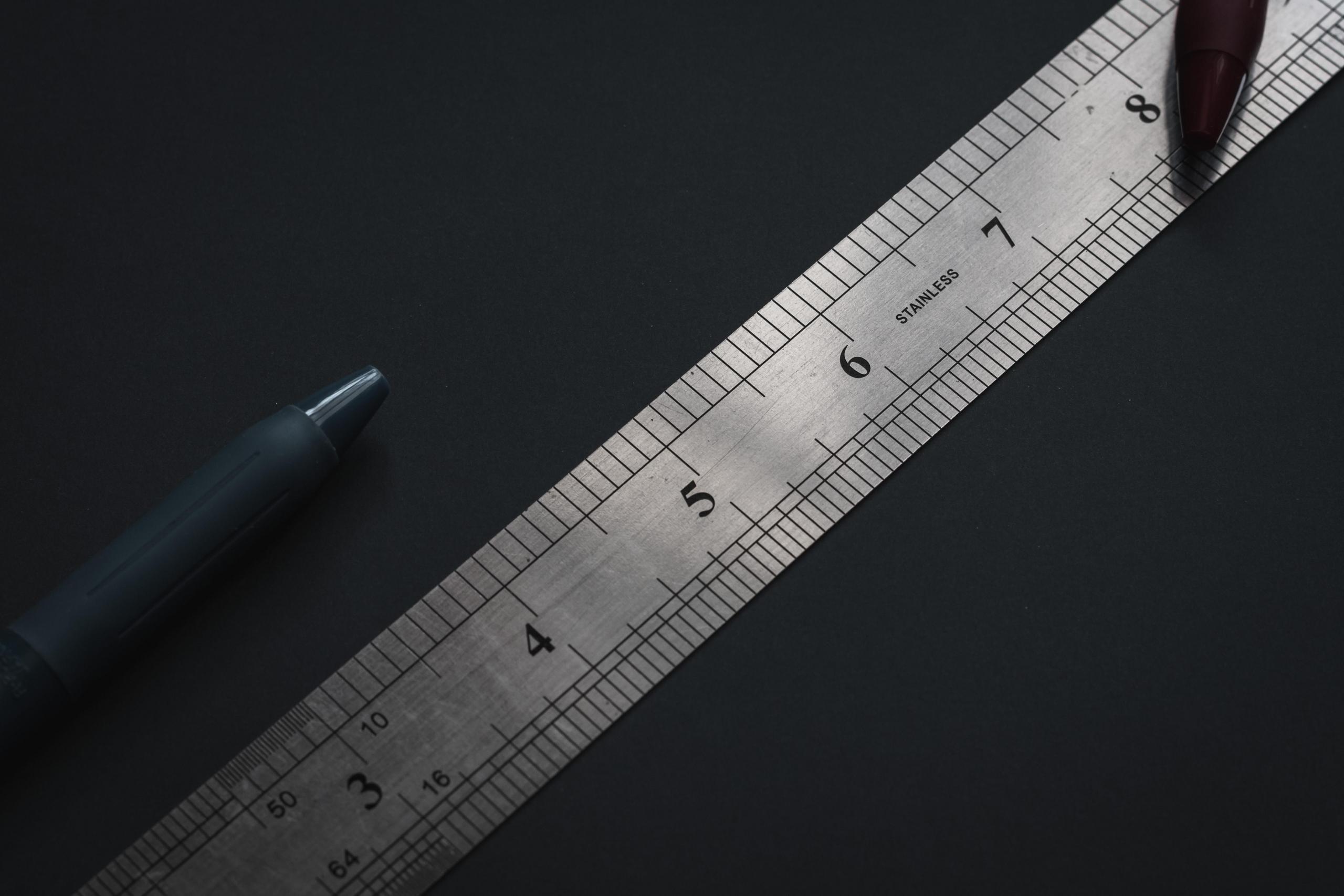 Metal ruler on desk with pens for sketching