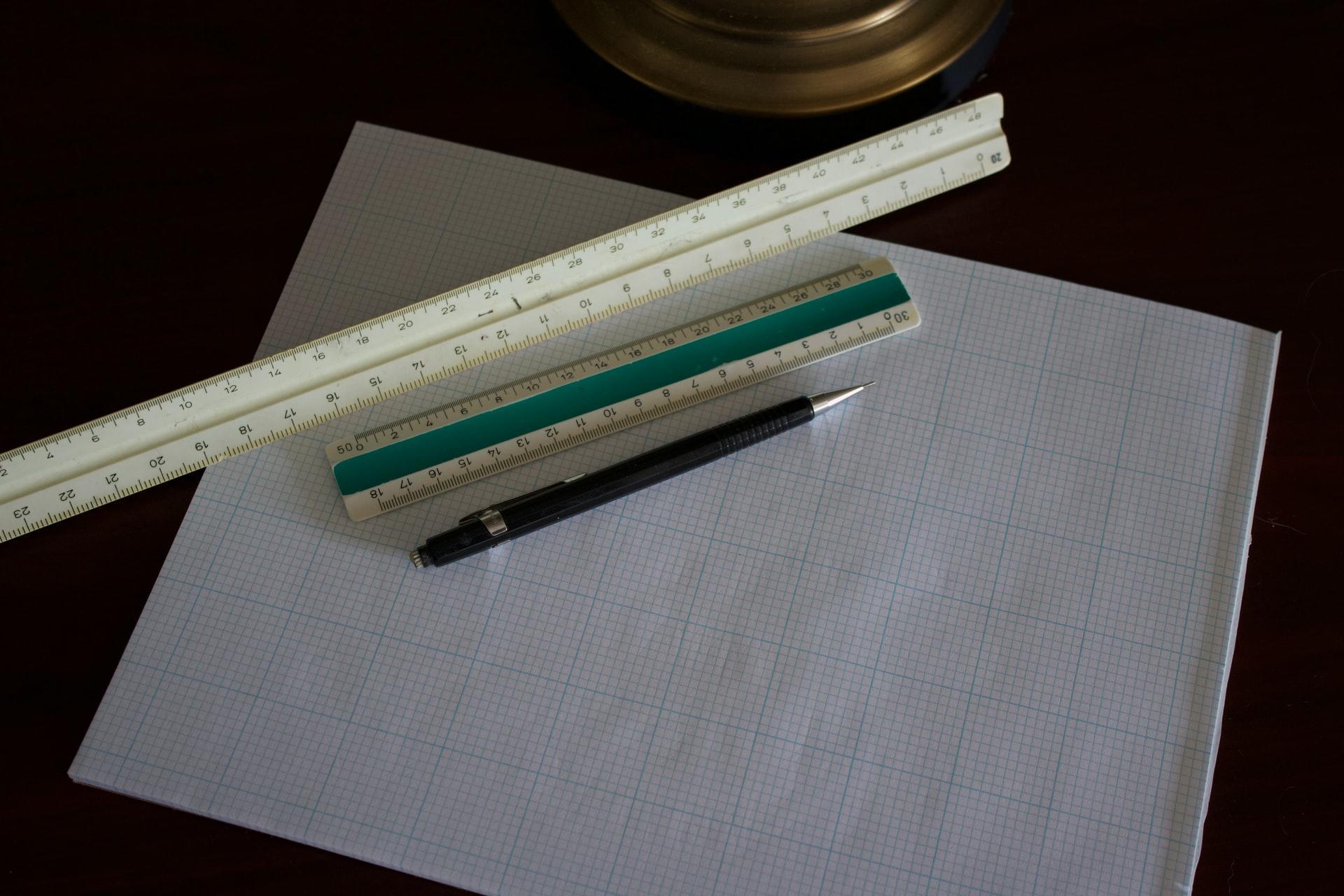 multiple rulers on a piece of graph paper with a pen