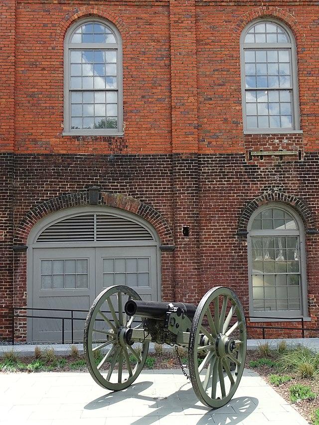 A cannon sitting outside a red brick building