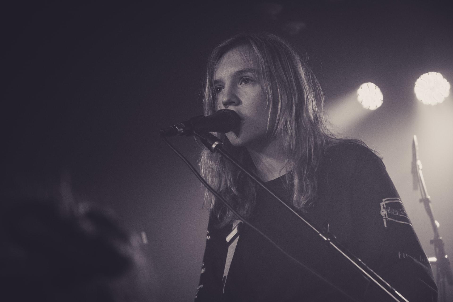 women wearing black shirt singing next to microphone