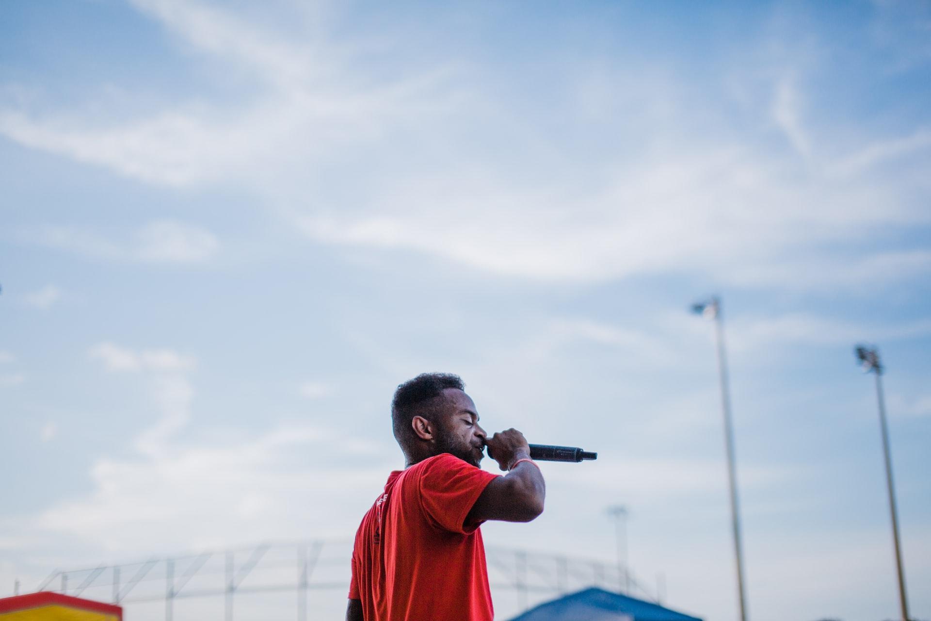 Man singing with microphone under blue sky