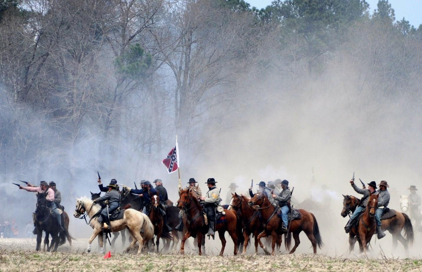 A depiction of a group of soldiers from the Civil War carrying rifles on horseback holding the Confederate flag. Albeit well trained, the Confederate soldiers were less in number and lacked access to the North's resources