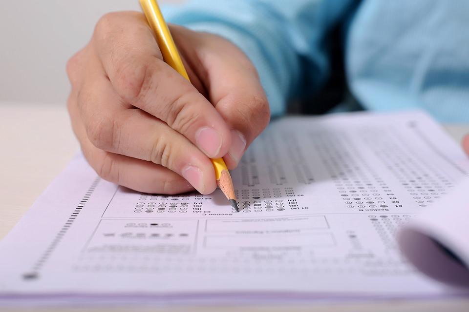 A person holding a pencil and attempting a multiple-choice questions test. The ACT English Practice Tests help the student understand the nature of the exam as they prepare to learn the testing pattern