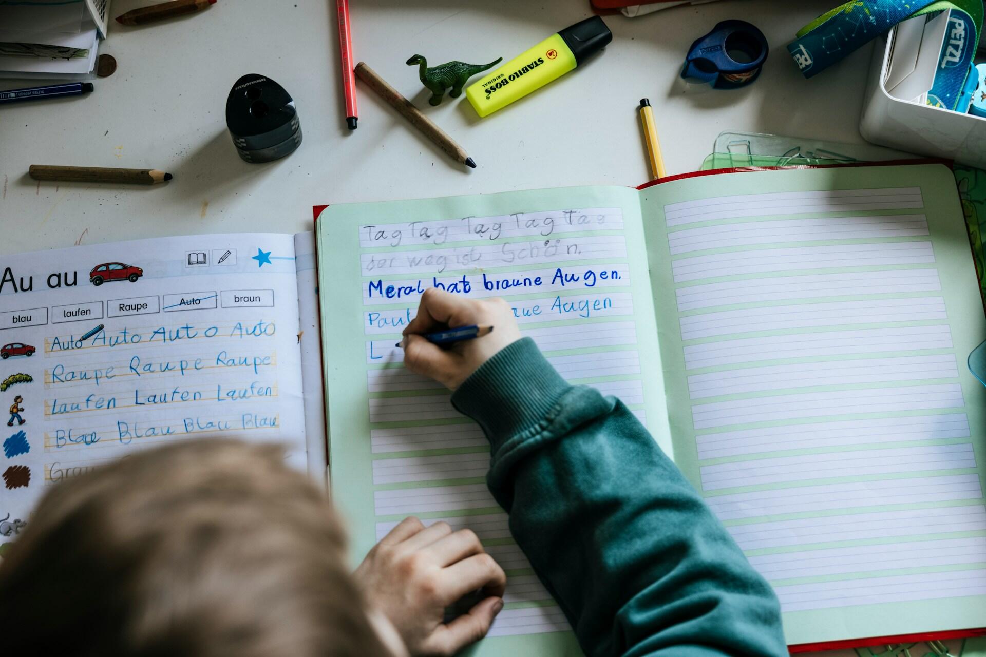 A child writing beginner German words.