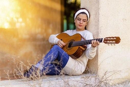 A student in a dress sitting on the grass playing the guitar. Colleges often fill their prospectuses with images of students enjoying university life to the fullest. Although this is true to some extent, there will also be tough days