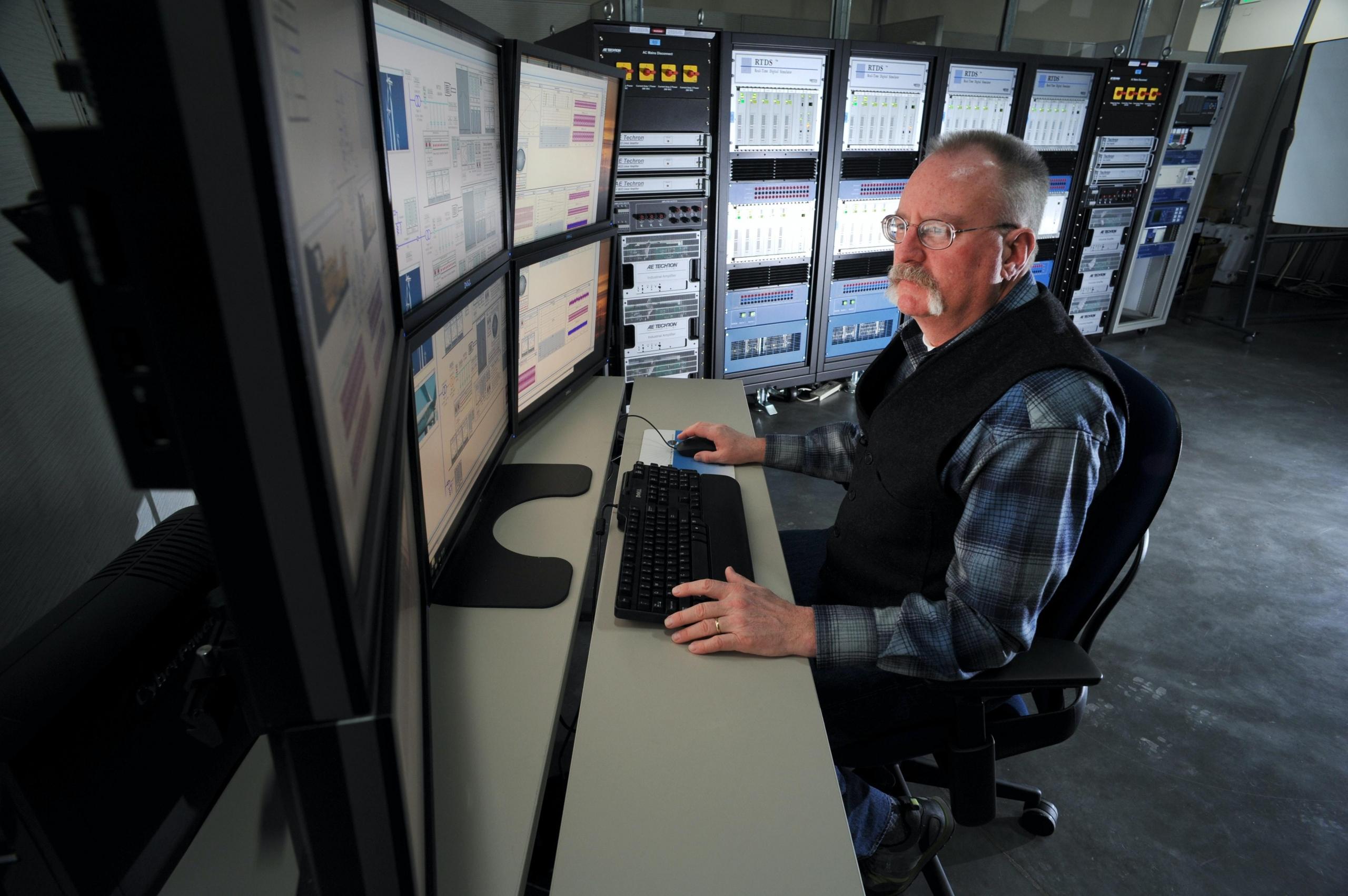 Man sitting in a server room using a computer. Computer science professionals are required to be familiar with the latest technological updates and innovations
