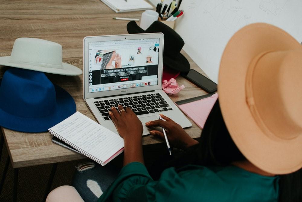 A woman in a hat using a Macbook air on a wooden table. If you plan to be working from home, you must have a high-speed internet connection. Technology stands to be the biggest roadblock for new WFH employees, but this problem should find its own solution