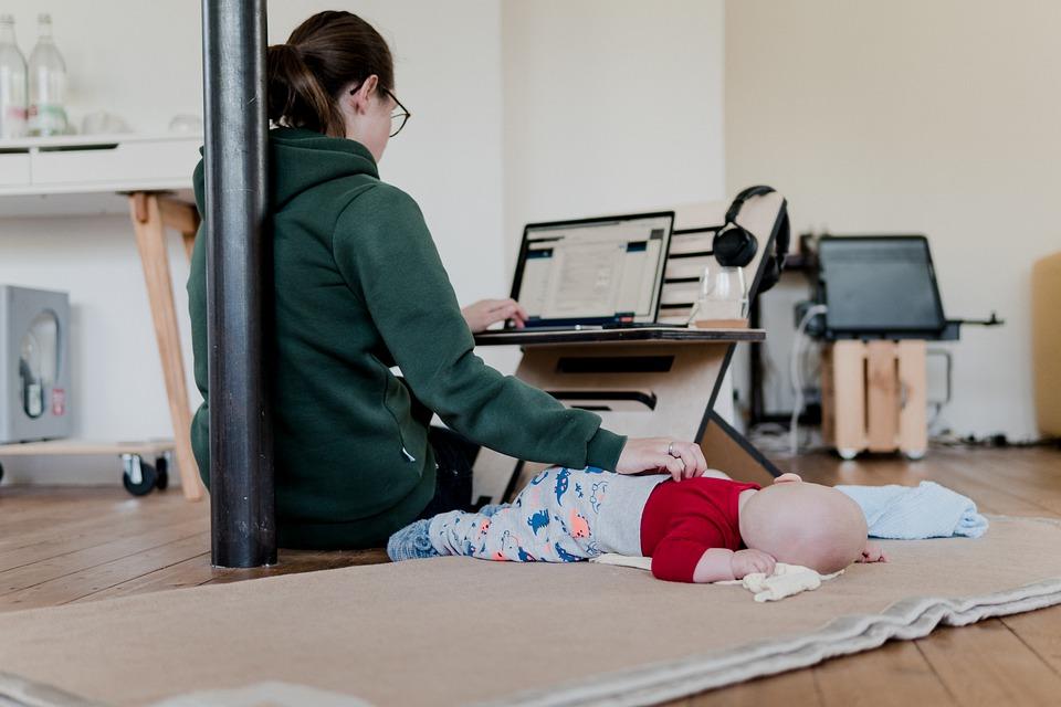 A mother putting her baby to sleep while working on her laptop. The added benefit of being able to focus on your primary responsibilities as a human is probably the best part of working from home