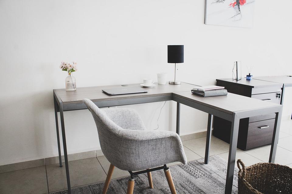 A home office study. A laptop, notebooks, lamp, cup, and vase with a flower are arranged on the table. The most crucial aspect of WFH is carrying forward the discipline of working in an office and maintaining it for the foreseeable future