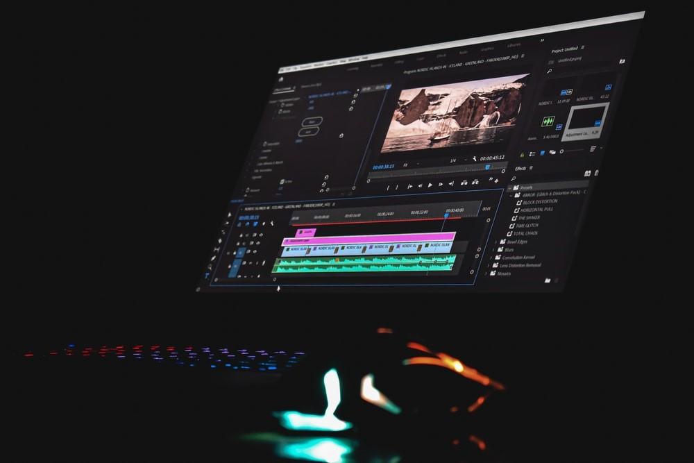 Adobe After Effects open on a screen; the background is dark except the lights on the keyboard and mouse, reflecting a combination of red-to-blue color palate. Being a designer can some times mean long hours; however, the career progression is worth it