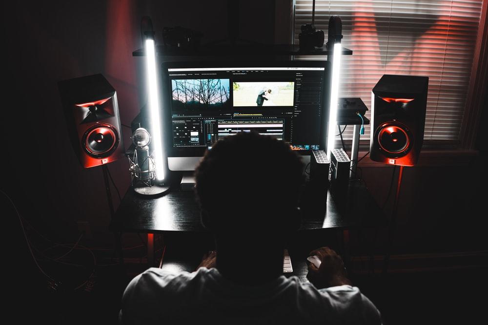 A man in a dark room sitting on a chair working on a computer. Adobe After Effects price is reasonable enough for freelance users on a tight budget who wish to use it for their projects; however, if you don't know how to use it, you may have to spend some time learning it
