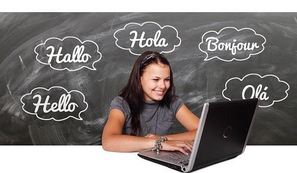 A girl revising what she has learned by using a French-language guide. There is a laptop in front of here and a blackboard in the background. French is one of the United Nation's official languages, giving it a lot of diplomatic importance