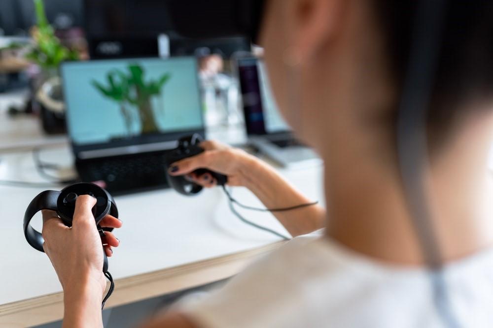 A person using two electronic equipment connected to the laptop in front of her. They are playing an interactive game, the kind that's available for children who are learning to code