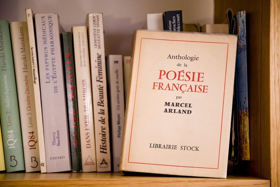 Numerous French books can be seen organized in a portion of the bookshelf. There is a book in the front on French poems by Marcel Arland. There are multiple other books, mostly related to French literature
