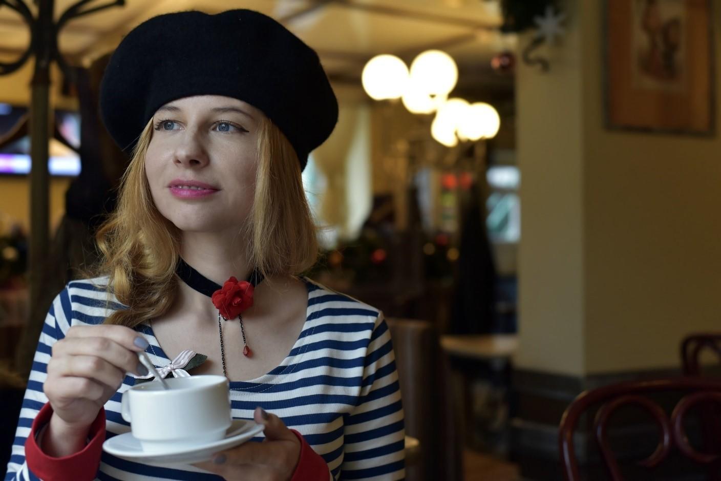 A brunette girl in a striped shirt has a cup of tea while sitting in a café during the daytime. If you're thinking of taking an exchange program to France, it's a wise idea to sign up for some French language lessons