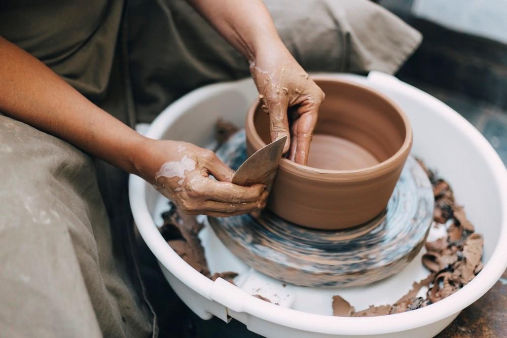 A person working on a clay pot on a pottery wheel. A potter’s wheel is an essential part of every pottery course, and beginners will be expected to know their way around this device. Although there is nothing to worry about, introductory courses teach students how to use these