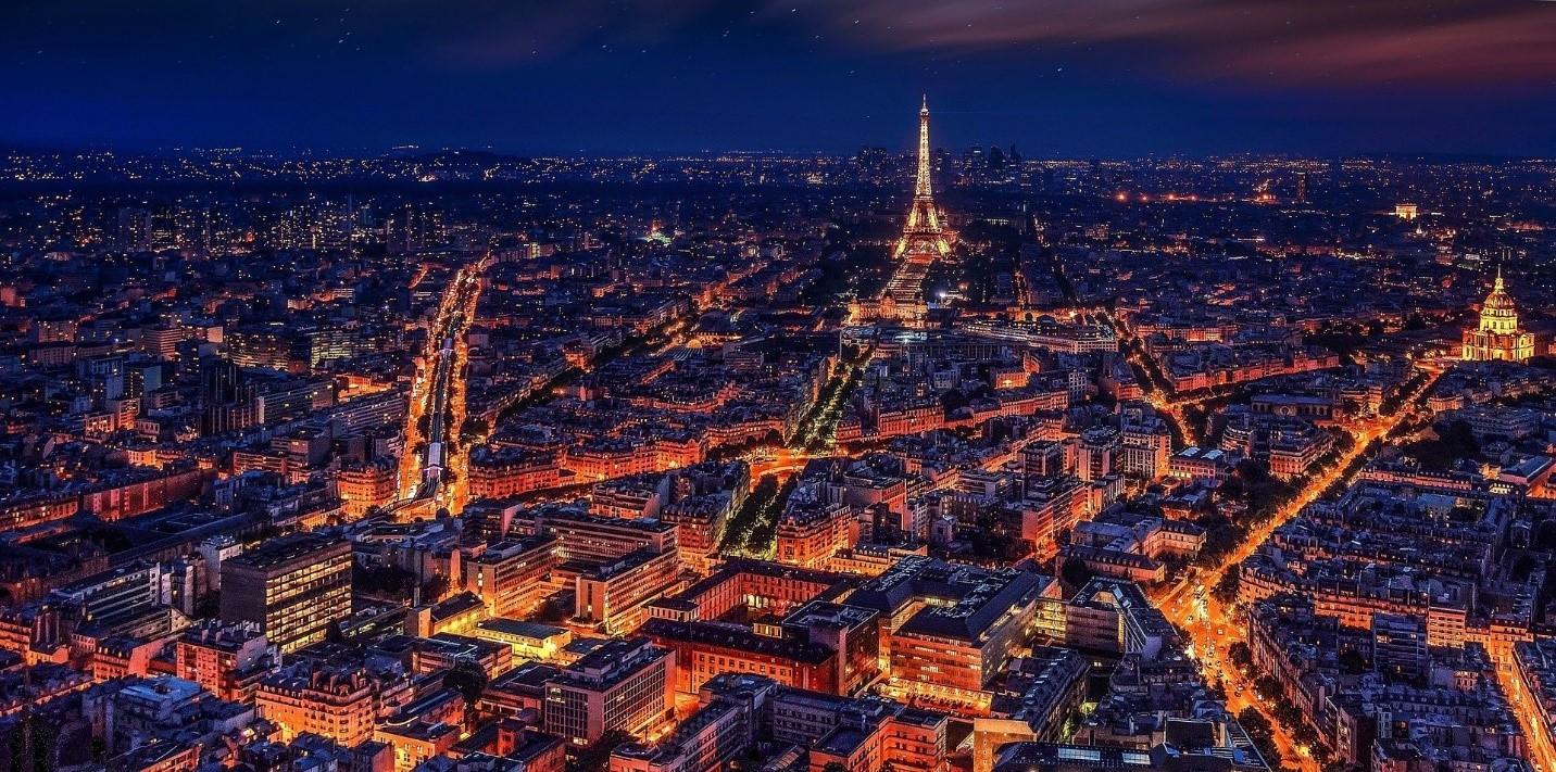 A photograph of Parisian buildings taken during the evening from a rooftop with the Eifel Tower in the background. If you want to experience Paris like a native, taking an introductory course in French is a good idea