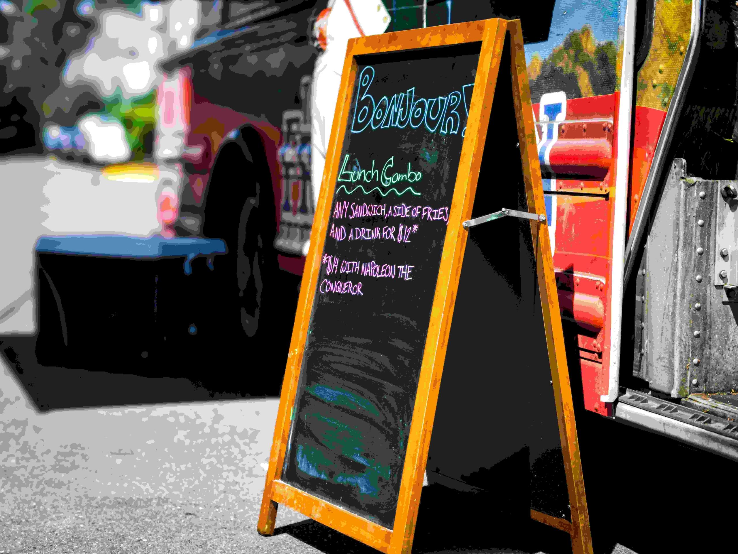 A small wooden blackboard with lunch combos written in pink, green, and blue chalk outside a local restaurant in Paris. One of many benefits of learning French is that you'll be able to communicate with locals as you navigate the streets of Paris