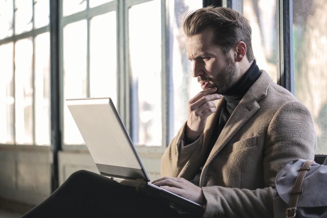 A man is sitting down, focused on the laptop in his lap. However, you do not have to worry when you look at that code because Superprof has the perfect computer programming tutor available for you