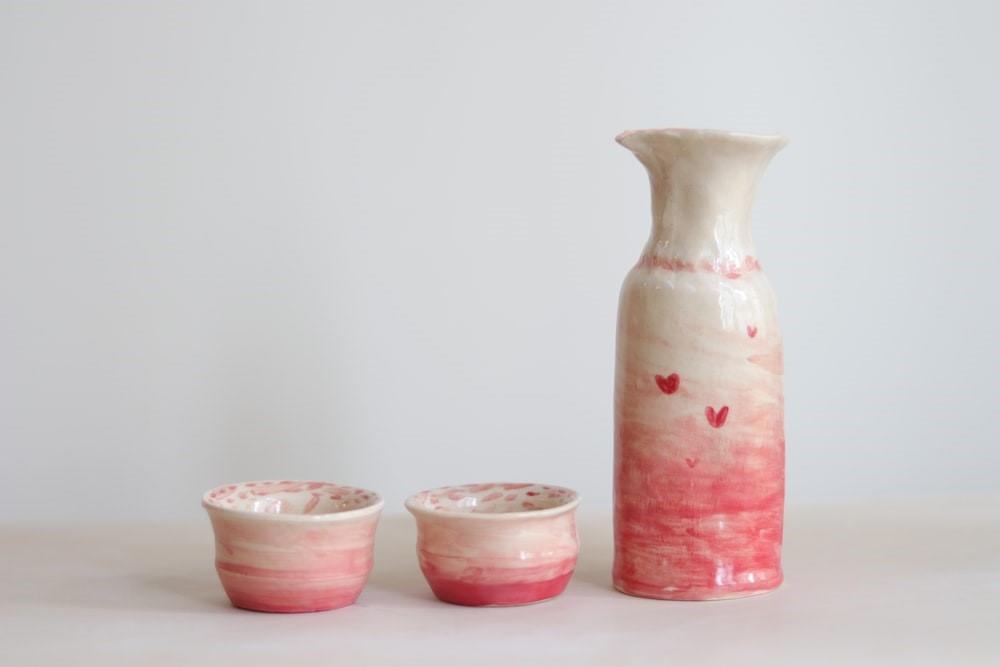 A pink and white pitcher and two bowls on a white surface. The good thing about pottery is that you can always rework your product as long as you haven’t fired it in the kiln. And everything you create can have some practical usage to boot