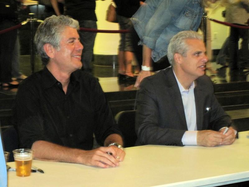 Renowned chefs Anthony Bourdain and Eric Ripert sitting together. Even though Bourdain is American and Ripert is French, they got along very well and went on many trips together. This was made easy due to the time Bourdain spent in France, acclimating to the culture