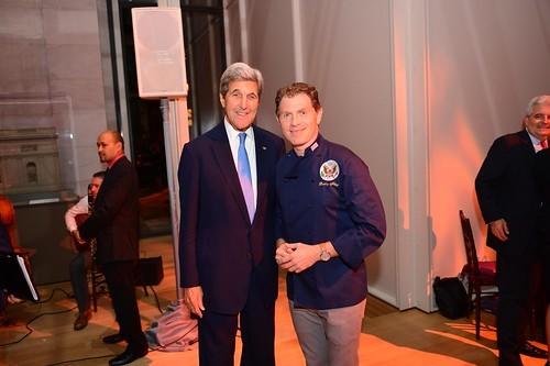 Bobby Flay standing next to Congressman John Kerry at an event. Bobby Flay participated in the Young Men's Barbecue, held at the White House in 2009, and later went on to cook dinner for Obama exclusively in 2013