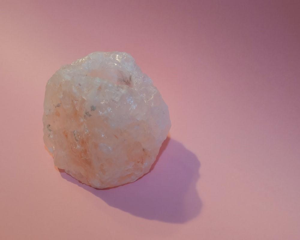 A white and brown mineral stone fragment lying on a pink surface. The study of geology involves working with rocks and minerals to determine their composition. Geology and Geochemistry are some of the many chemistry-related careers