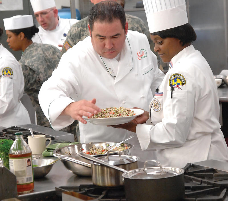 Emeril Lagasse working with Staff Sgt. Michelle Hall, working at the Army Center of Excellence as a food service instructor. He is known to be very patient and a good teacher