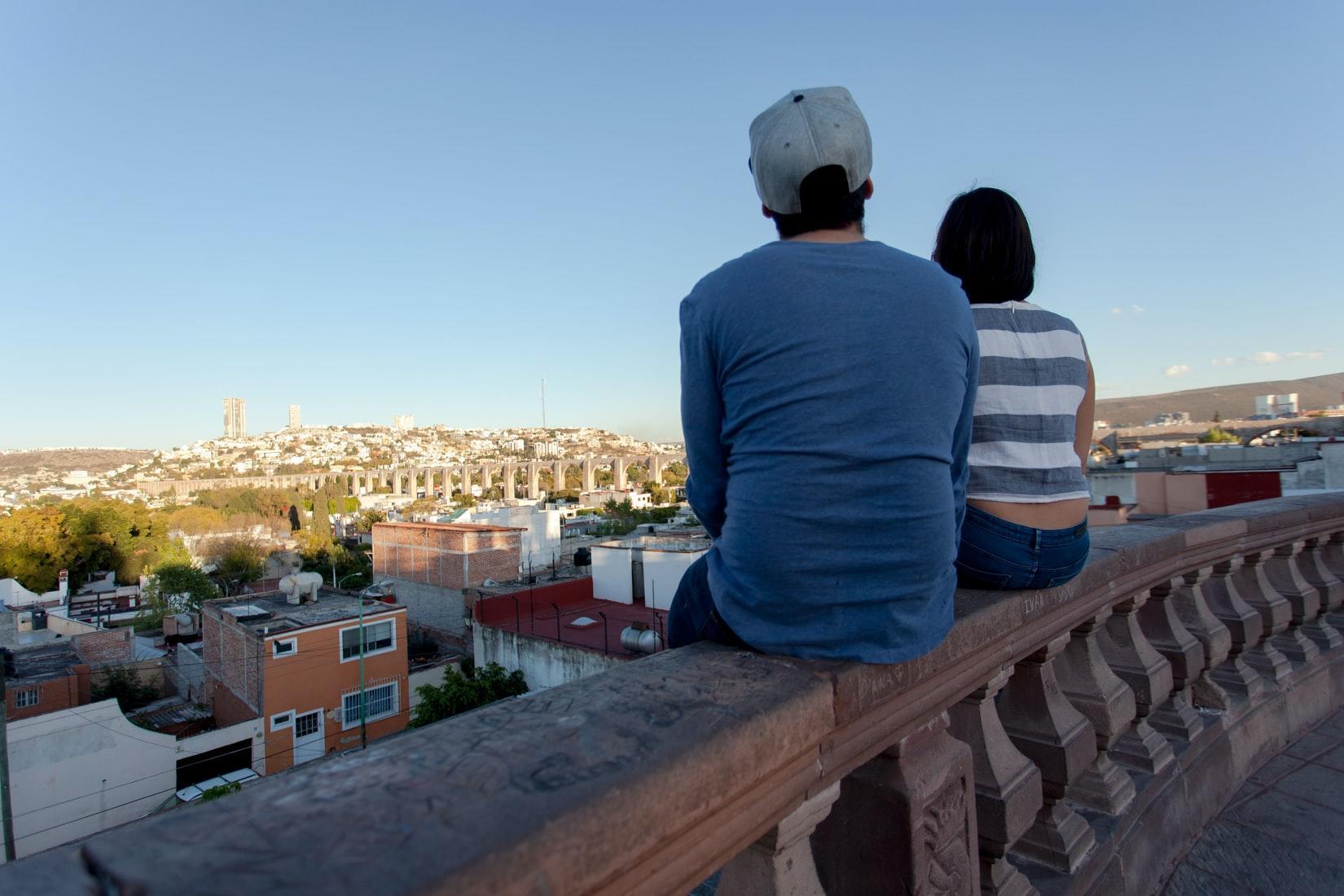 Two people sitting on a ledge overlooking the city. Studying Spanish in Mexico does not only mean you will become a master of the language, but you will also have a lot of fun exploring as you learn the language.